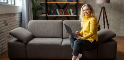 Mujer sentada en un sillón con computador en las piernas