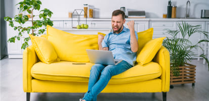 Hombre sentado en un sillón con computador en las piernas